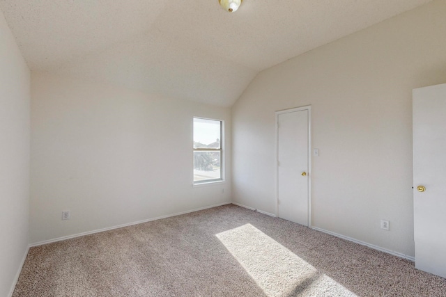 carpeted empty room with lofted ceiling and a textured ceiling