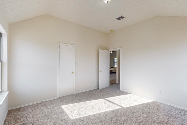 unfurnished bedroom featuring lofted ceiling, light carpet, and a textured ceiling