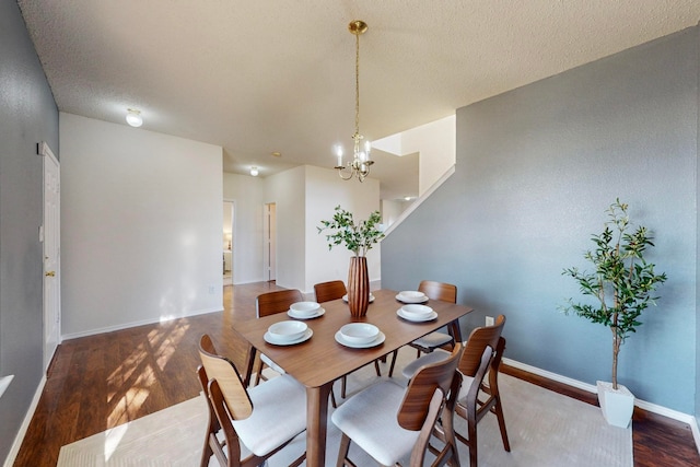 dining room with a textured ceiling, dark hardwood / wood-style flooring, and an inviting chandelier