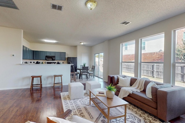 living room featuring dark wood-type flooring and a textured ceiling