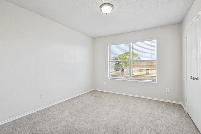 empty room featuring light carpet and a textured ceiling