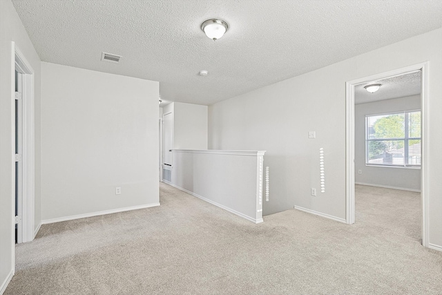 spare room featuring a textured ceiling and light colored carpet