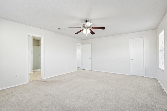 unfurnished bedroom featuring light carpet, a textured ceiling, a closet, and ceiling fan