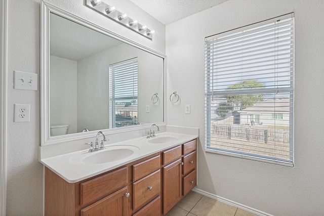 bathroom with a healthy amount of sunlight, vanity, a textured ceiling, and toilet