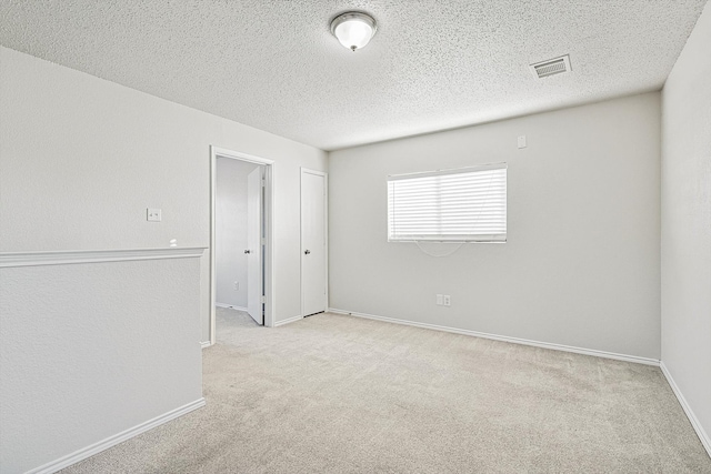 spare room featuring a textured ceiling and light colored carpet