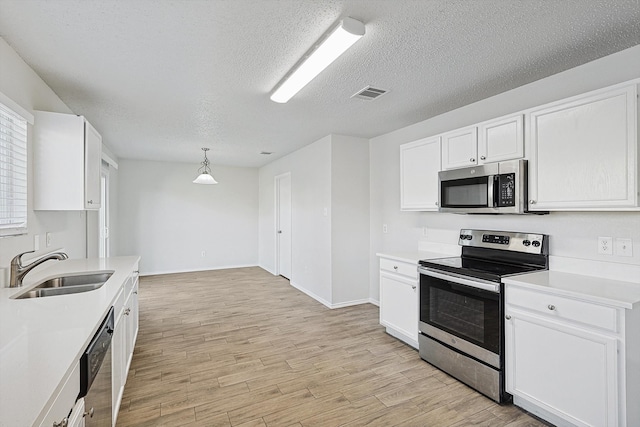 kitchen with sink, appliances with stainless steel finishes, light hardwood / wood-style flooring, and white cabinets