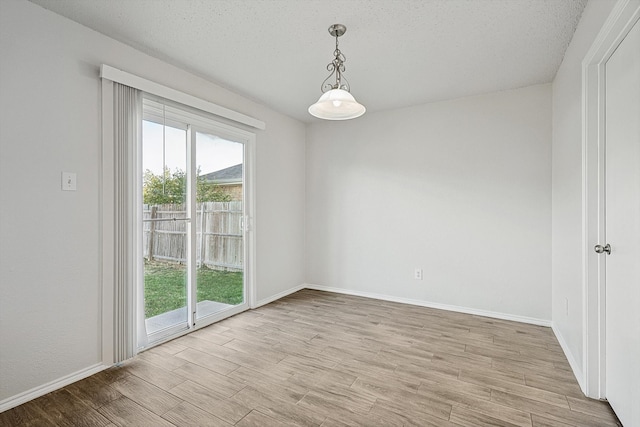 spare room with a textured ceiling and light hardwood / wood-style flooring