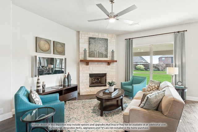 living room featuring a stone fireplace, hardwood / wood-style floors, and ceiling fan