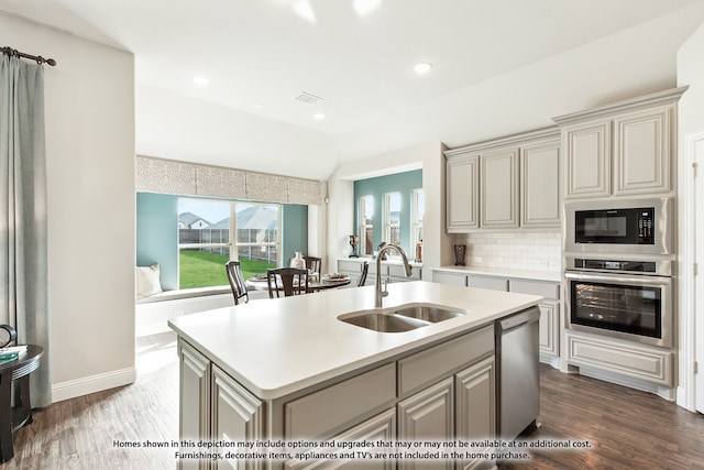 kitchen featuring dark wood-type flooring, appliances with stainless steel finishes, sink, and a kitchen island with sink