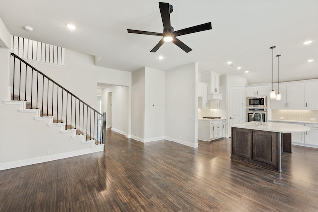 kitchen featuring dark wood-style floors, light countertops, open floor plan, built in microwave, and oven