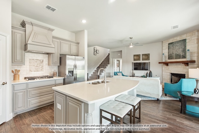 kitchen featuring sink, an island with sink, dark hardwood / wood-style flooring, stainless steel appliances, and custom exhaust hood