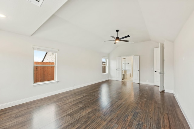 spare room featuring dark wood-style floors, lofted ceiling, a ceiling fan, and baseboards