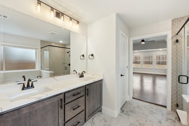 bathroom with marble finish floor, double vanity, a sink, and a shower stall