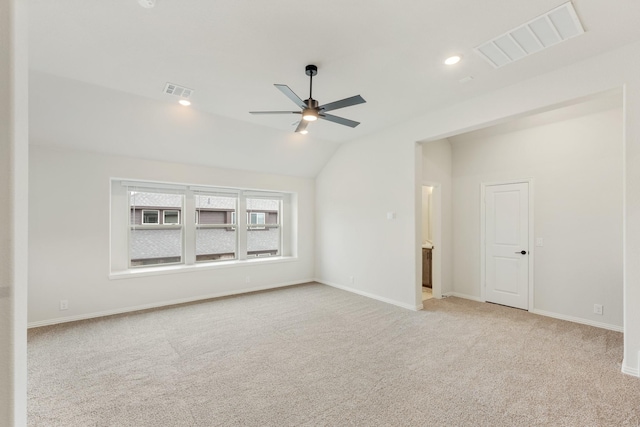 empty room featuring lofted ceiling, baseboards, visible vents, and light colored carpet