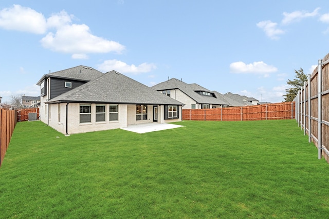 rear view of property with a patio, a fenced backyard, brick siding, a lawn, and roof with shingles