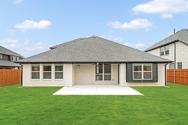 rear view of house featuring brick siding, roof with shingles, a lawn, a patio area, and a fenced backyard