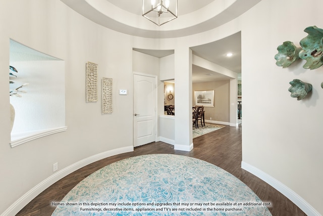 foyer featuring a notable chandelier, a raised ceiling, and dark hardwood / wood-style floors