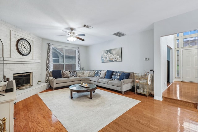 living room featuring ceiling fan, hardwood / wood-style flooring, and a fireplace