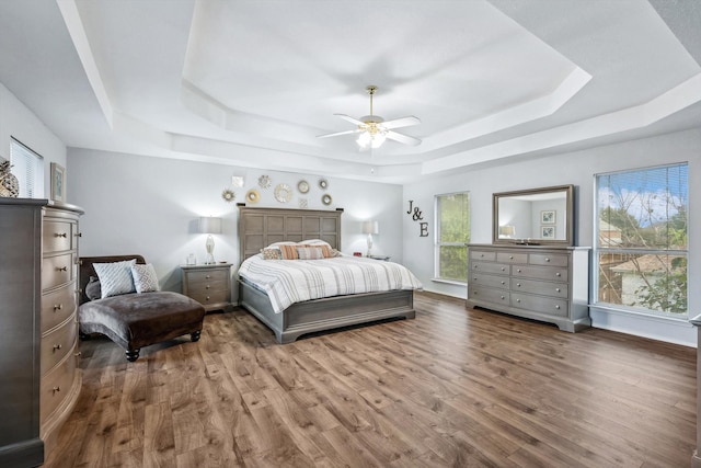 bedroom with dark hardwood / wood-style floors, a raised ceiling, and ceiling fan