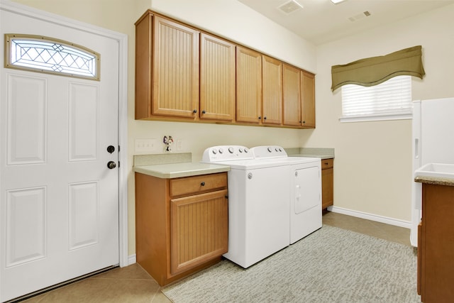 laundry room featuring cabinets, light tile patterned floors, and washing machine and clothes dryer