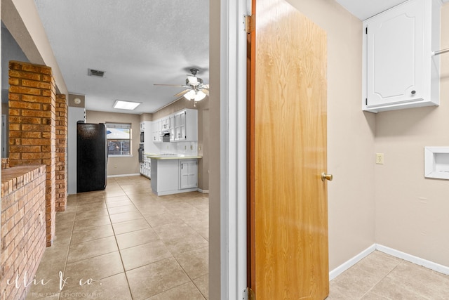 kitchen with black fridge, light tile patterned floors, white cabinetry, a textured ceiling, and ceiling fan