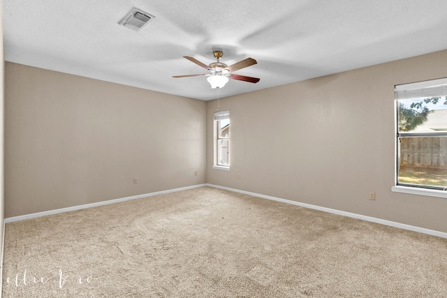 spare room with a textured ceiling, carpet flooring, and ceiling fan