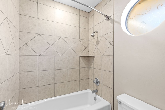 bathroom featuring tiled shower / bath combo and toilet