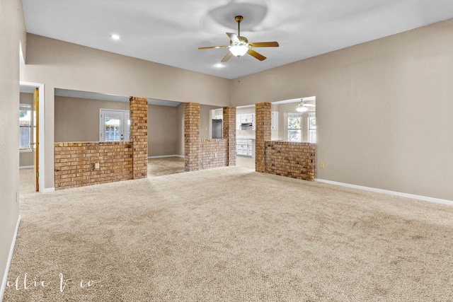 unfurnished living room with carpet floors, brick wall, and ceiling fan