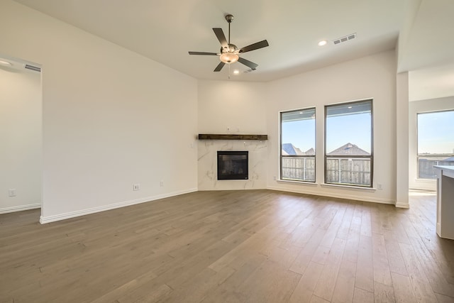 unfurnished living room with ceiling fan, wood-type flooring, and a fireplace