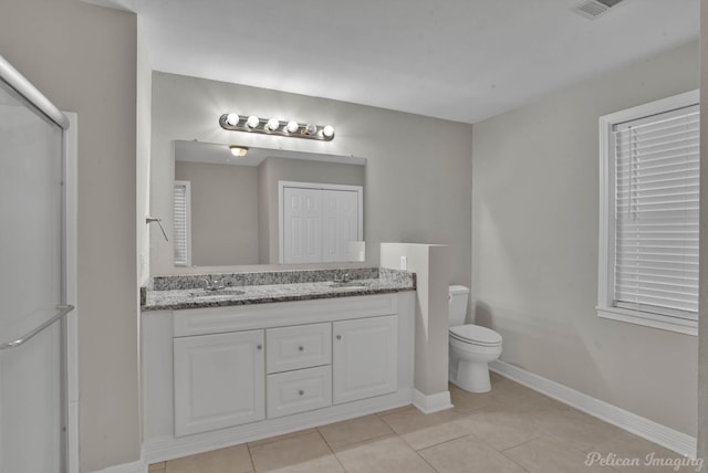 bathroom featuring toilet, vanity, tile patterned floors, and a shower with door