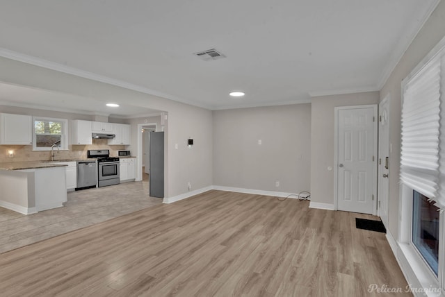 unfurnished living room featuring sink, light wood-type flooring, and ornamental molding