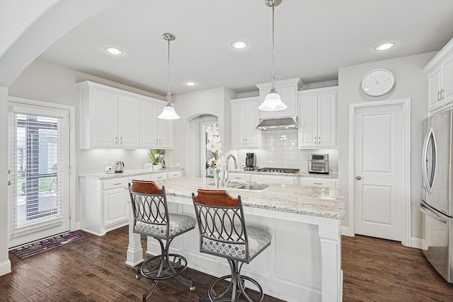 kitchen featuring pendant lighting, white cabinetry, stainless steel appliances, and an island with sink