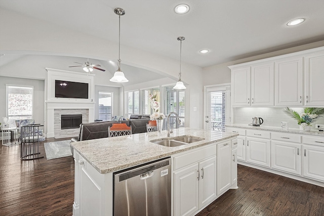 kitchen with white cabinetry, a kitchen island with sink, dishwasher, a fireplace, and sink