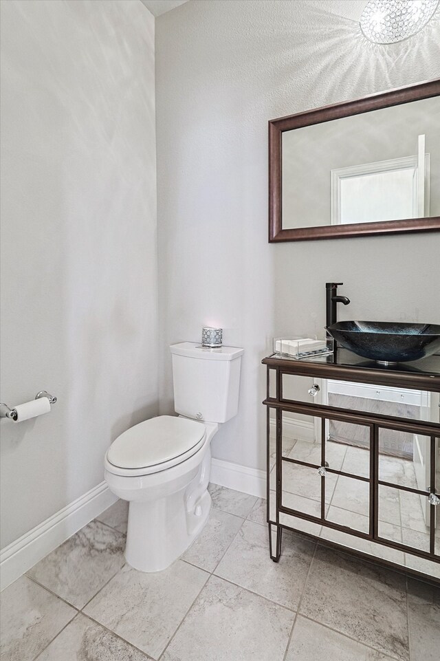 bathroom with sink, toilet, and tile patterned flooring