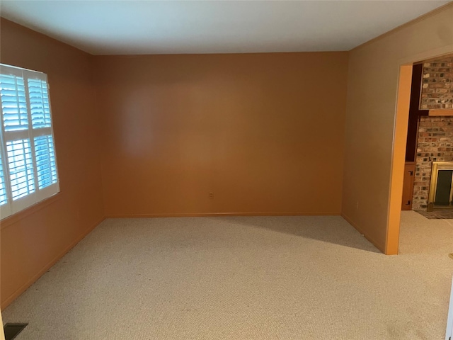 spare room with light carpet and a fireplace