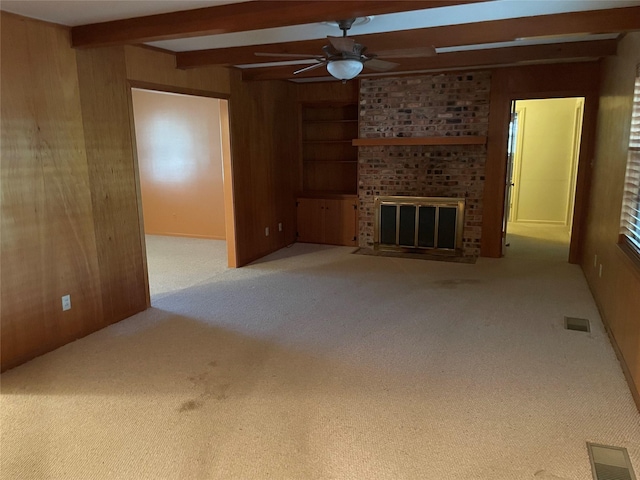 unfurnished living room featuring beam ceiling, wooden walls, a fireplace, and carpet