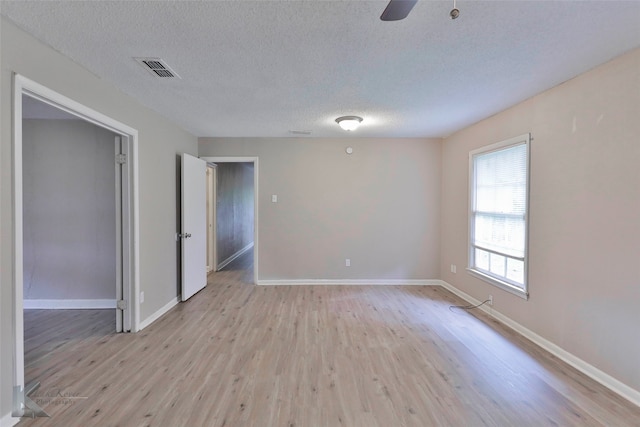 unfurnished room featuring a textured ceiling, light wood-type flooring, and ceiling fan