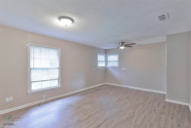 empty room with ceiling fan, a healthy amount of sunlight, a textured ceiling, and light hardwood / wood-style flooring