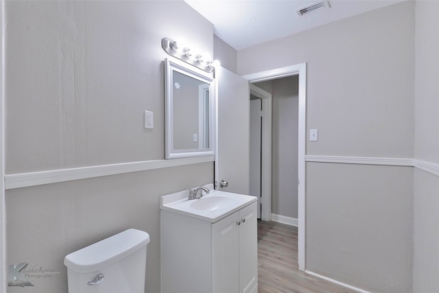 bathroom featuring toilet, vanity, and wood-type flooring