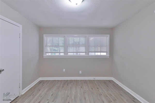 spare room featuring light hardwood / wood-style floors and a textured ceiling