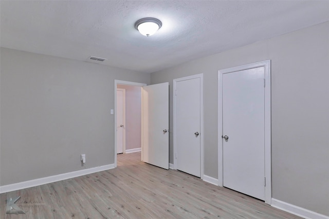 unfurnished bedroom with a textured ceiling and light hardwood / wood-style floors