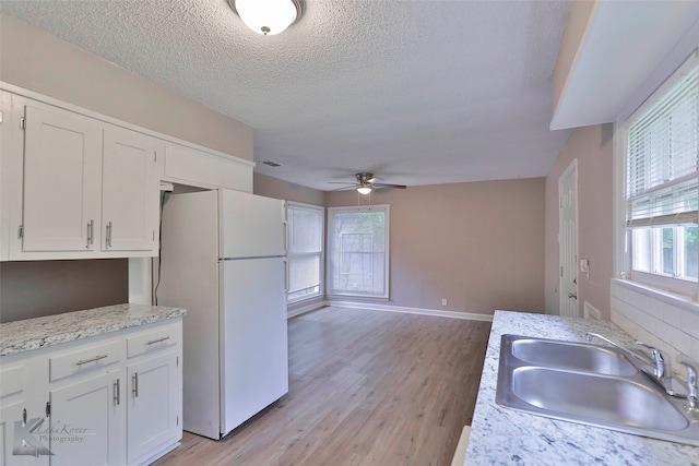 kitchen with sink, light wood-type flooring, white cabinetry, white fridge, and ceiling fan