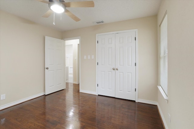 unfurnished bedroom with ceiling fan, a textured ceiling, and dark hardwood / wood-style flooring