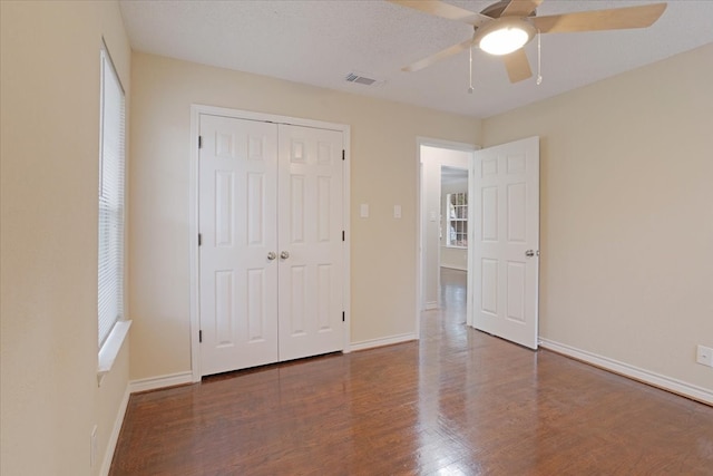 unfurnished bedroom featuring a closet, ceiling fan, a textured ceiling, and dark hardwood / wood-style floors