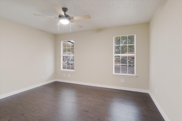 empty room with a wealth of natural light, a textured ceiling, dark hardwood / wood-style floors, and ceiling fan