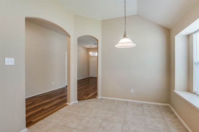 tiled empty room featuring lofted ceiling