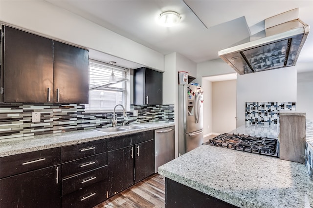 kitchen featuring exhaust hood, backsplash, sink, light wood-type flooring, and appliances with stainless steel finishes