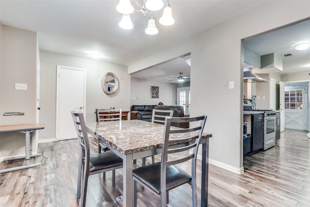 dining room with light hardwood / wood-style floors and ceiling fan with notable chandelier