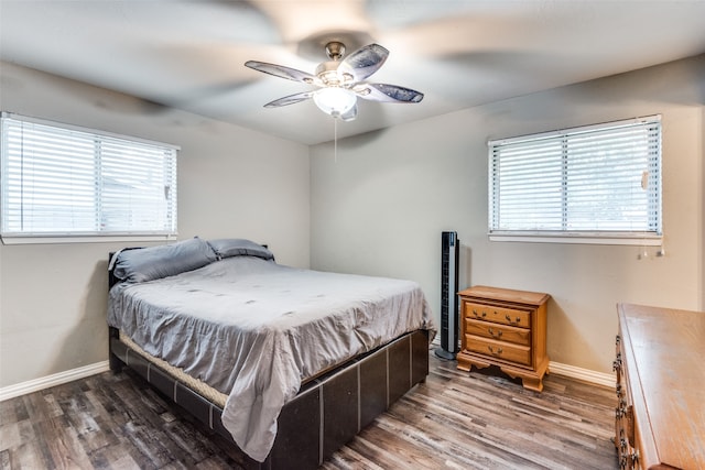 bedroom with multiple windows, dark hardwood / wood-style floors, and ceiling fan