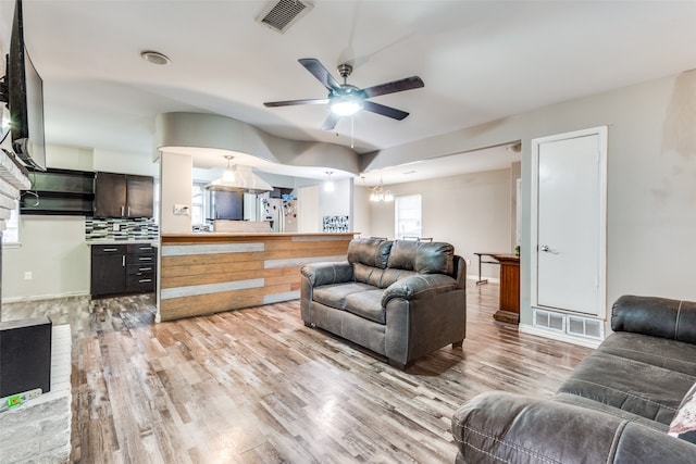 living room featuring light hardwood / wood-style floors and ceiling fan with notable chandelier